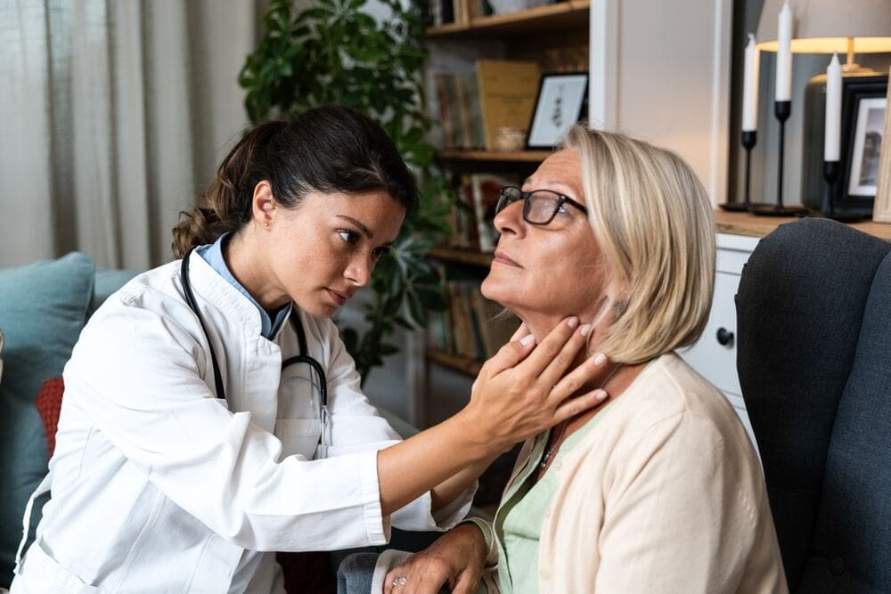 A thyroid doctor palpates a patient’s thyroid