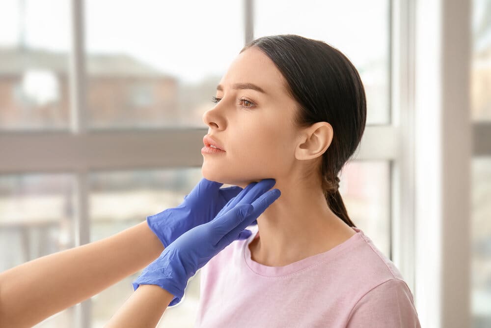 An endocrinologist examines a female patient to check for thyroid nodules