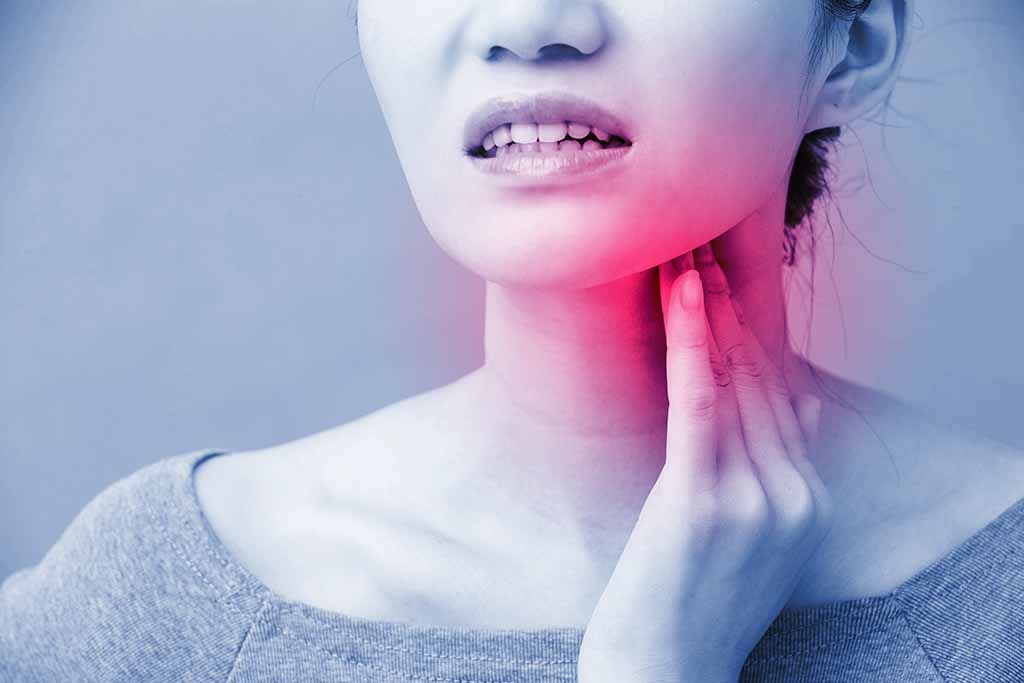 A woman touches her tender thyroid, which radiates with a soft red glow