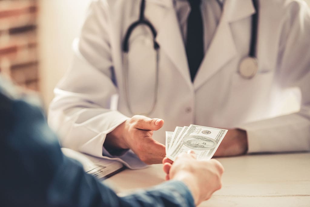 Cropped image of a patient handing cash to a physician